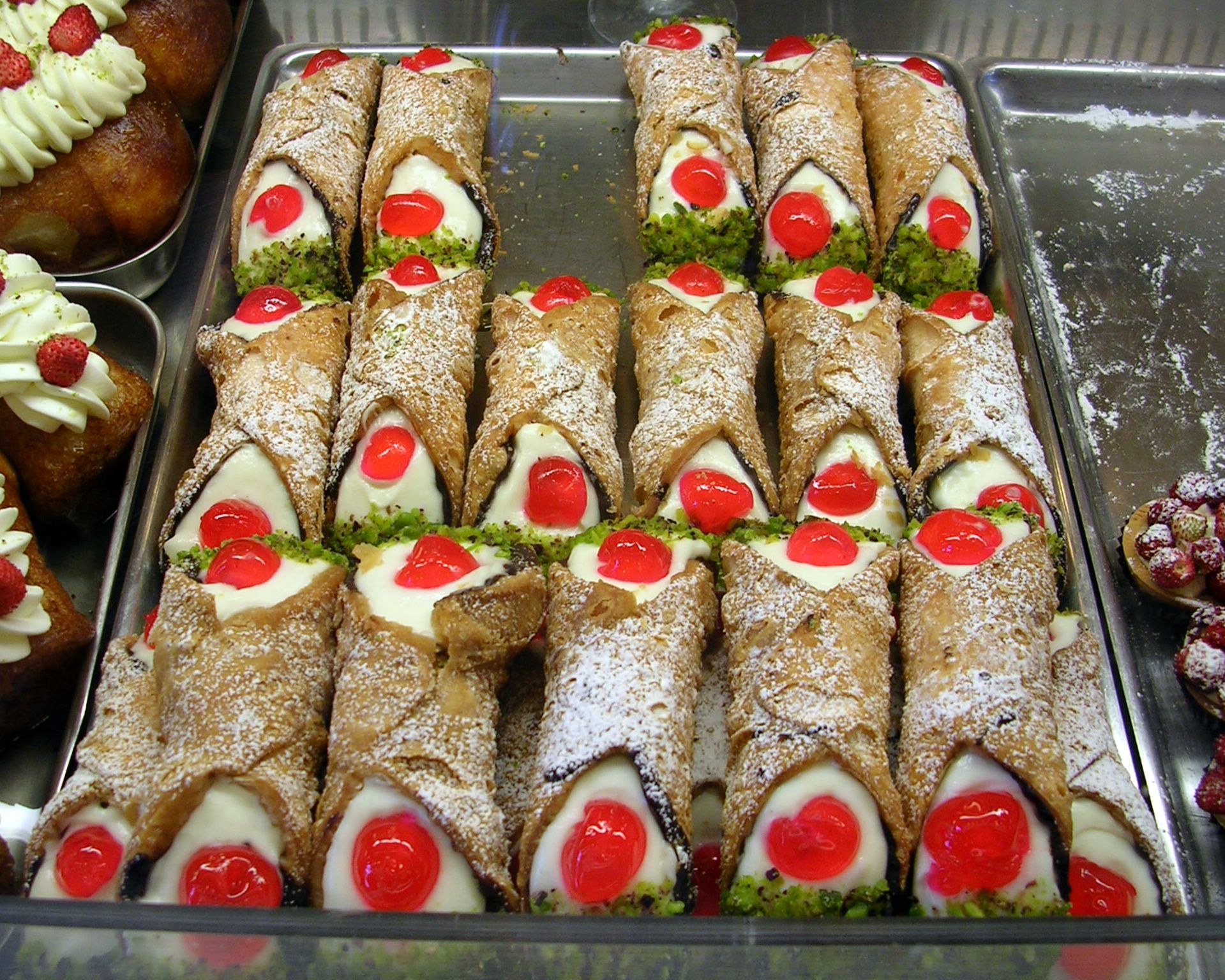 Vassoio di cannoli siciliani ripieni di ricotta con ciliegie candite e granella di pistacchio